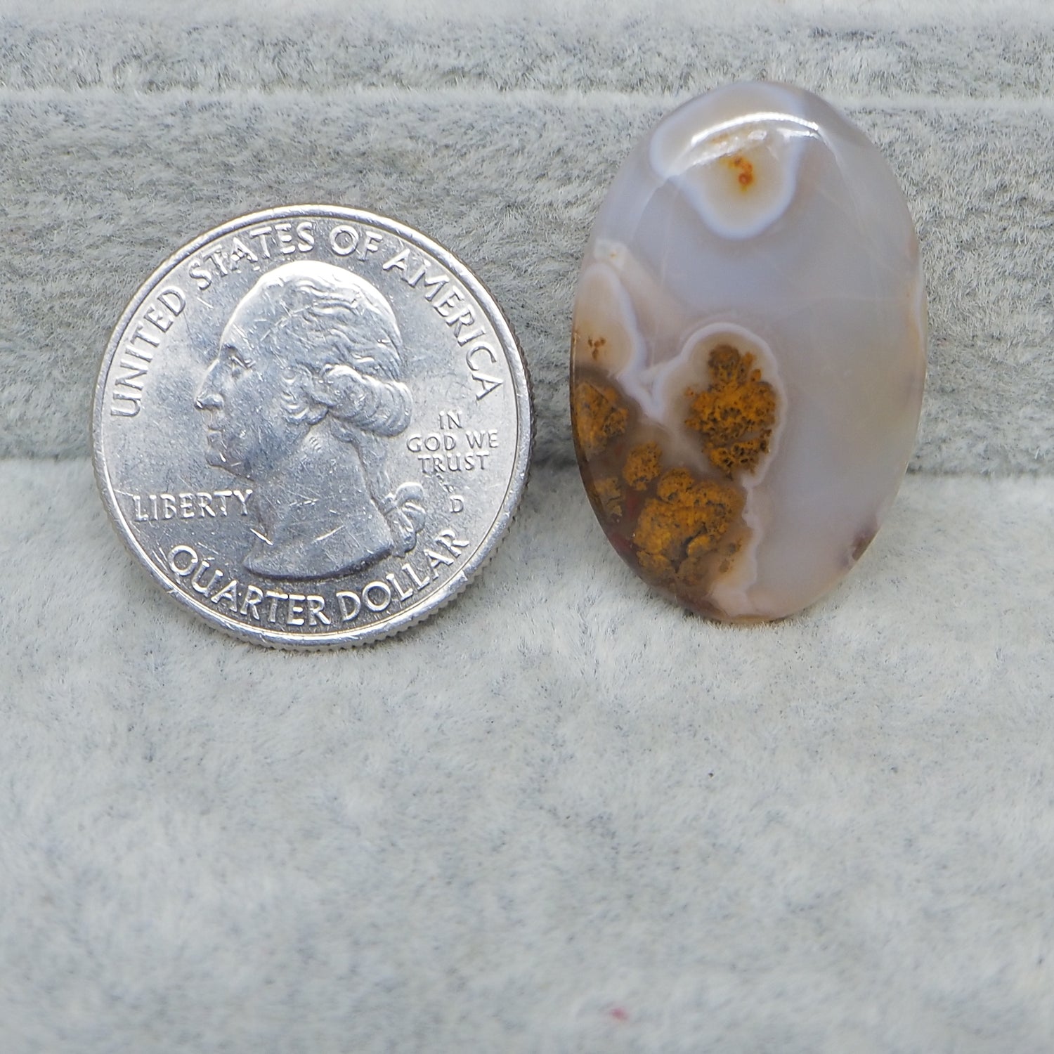 Agate stone next to a U.S. quarter dollar on a textured surface