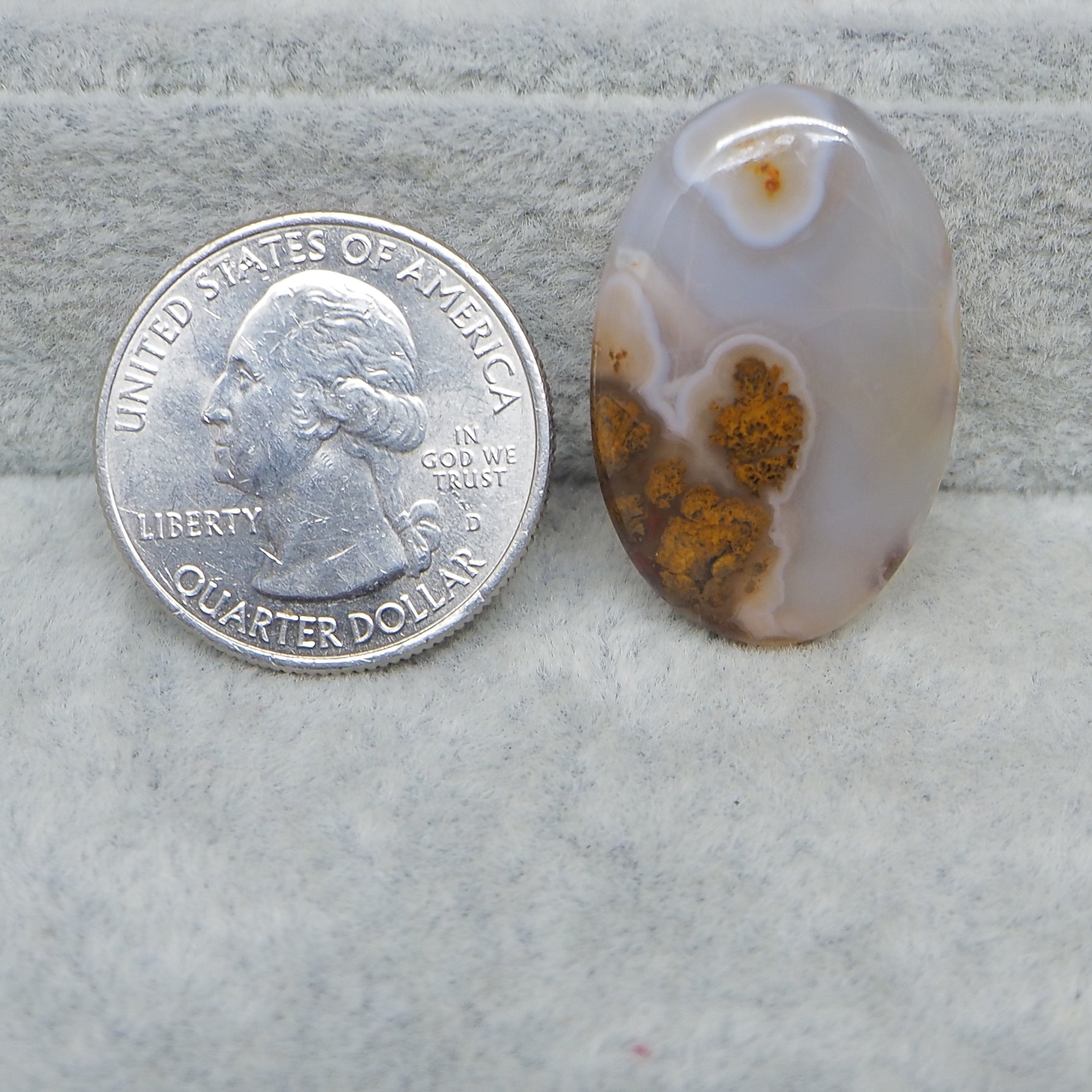 Agate stone next to a U.S. quarter dollar on a textured surface