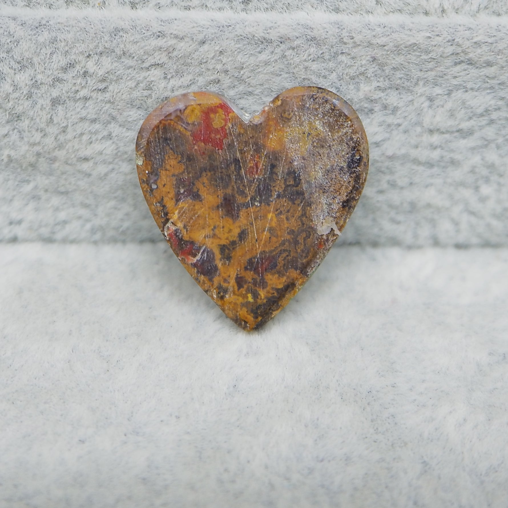 Heart-shaped stone with rust-like patterns on a textured surface