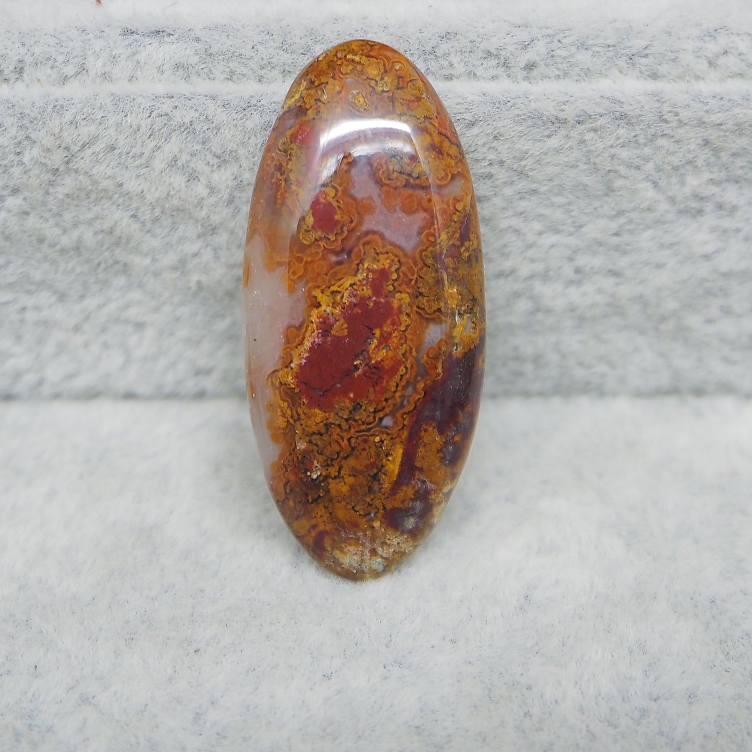 Oval-shaped jasper stone on a textured gray background