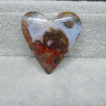 Heart-shaped stone with multicolored patterns on a textured surface