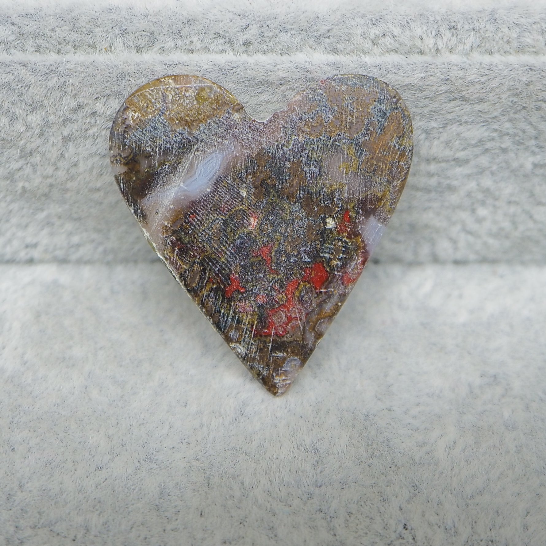 Heart-shaped stone with a textured surface on a gray stone background