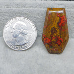 Close-up of a colorful stone next to a U.S. quarter dollar on a gray surface