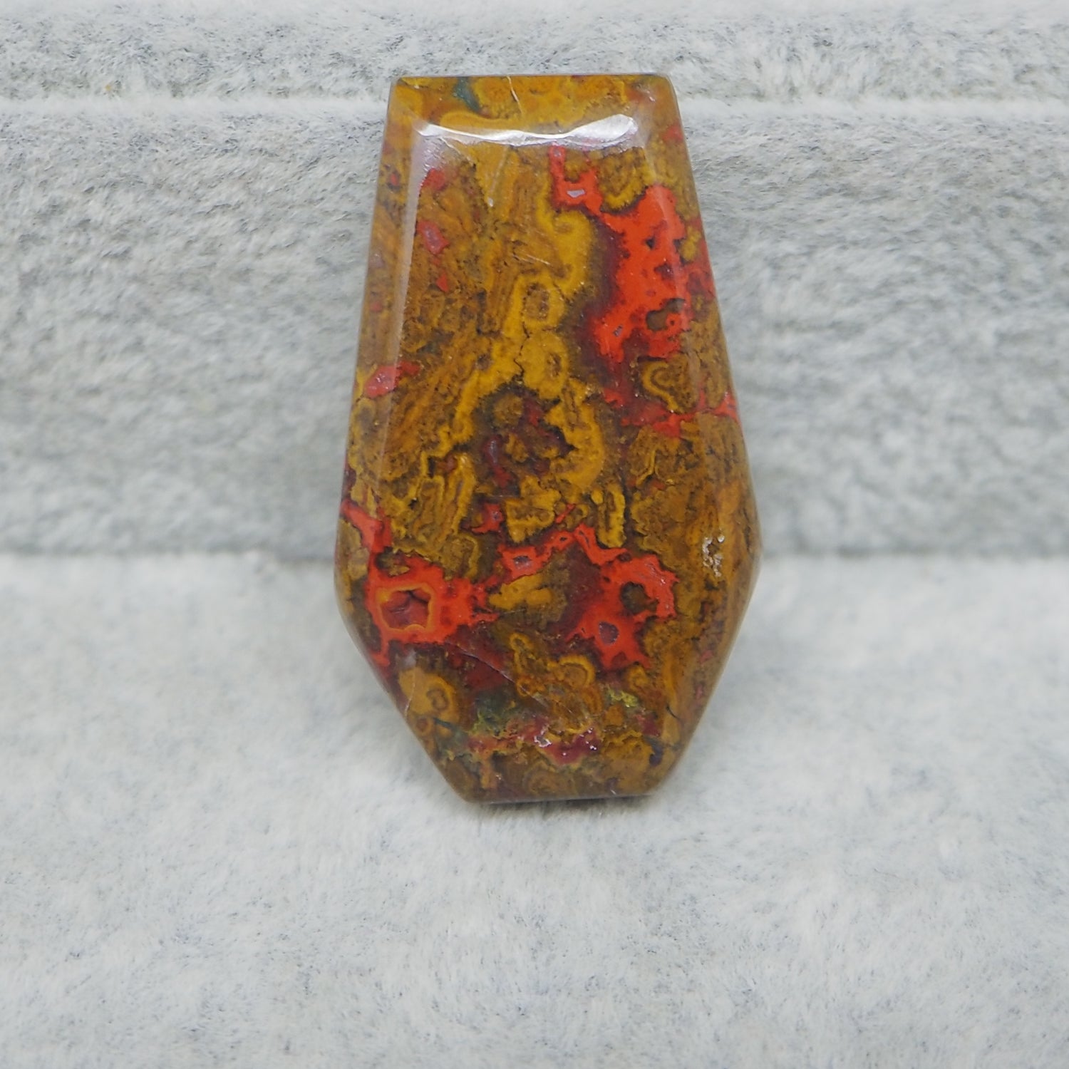 Decorative stone with red and yellow patterns on a textured gray surface