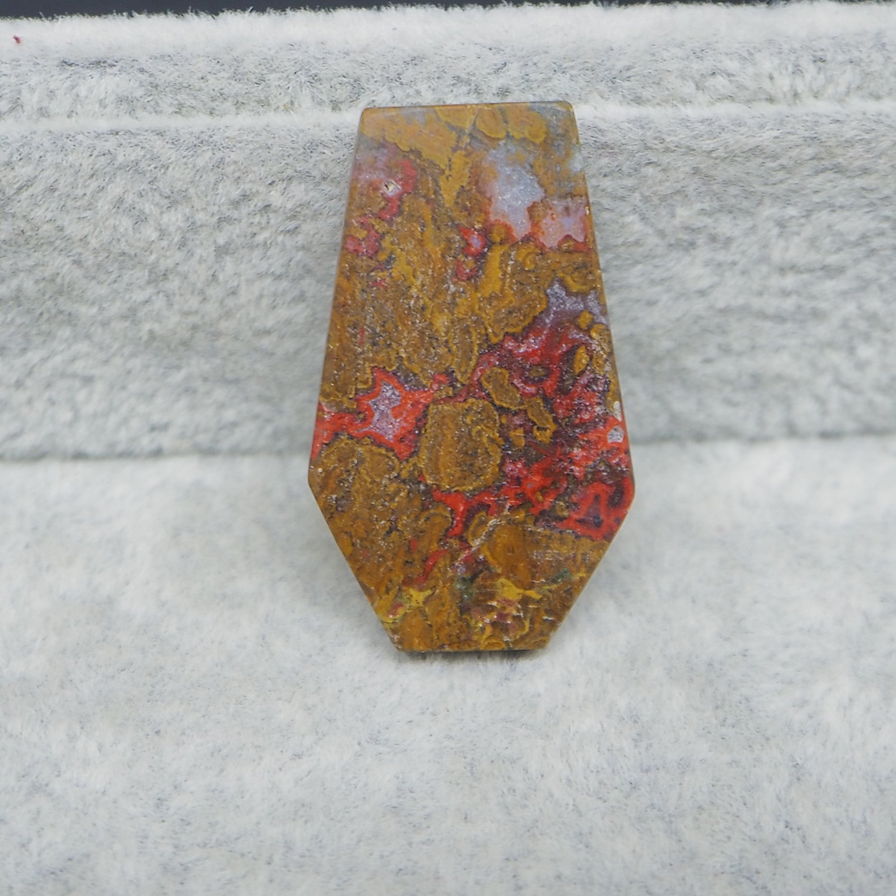 Decorative stone with red and yellow patterns on a textured gray background