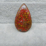 Teardrop-shaped red and yellow patterned stone on a textured gray surface