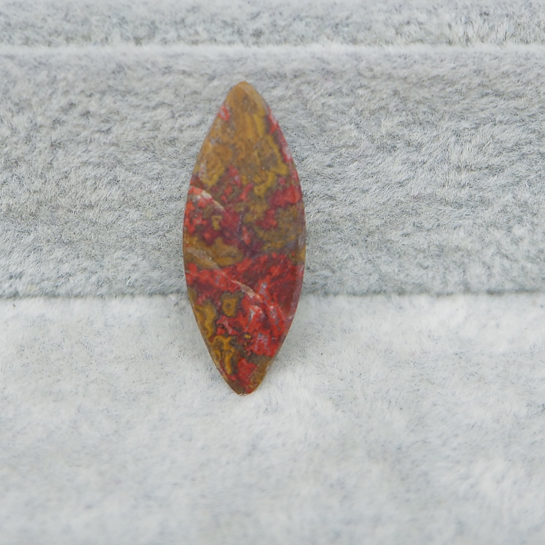 Decorative stone with red and gold patterns on a textured gray surface