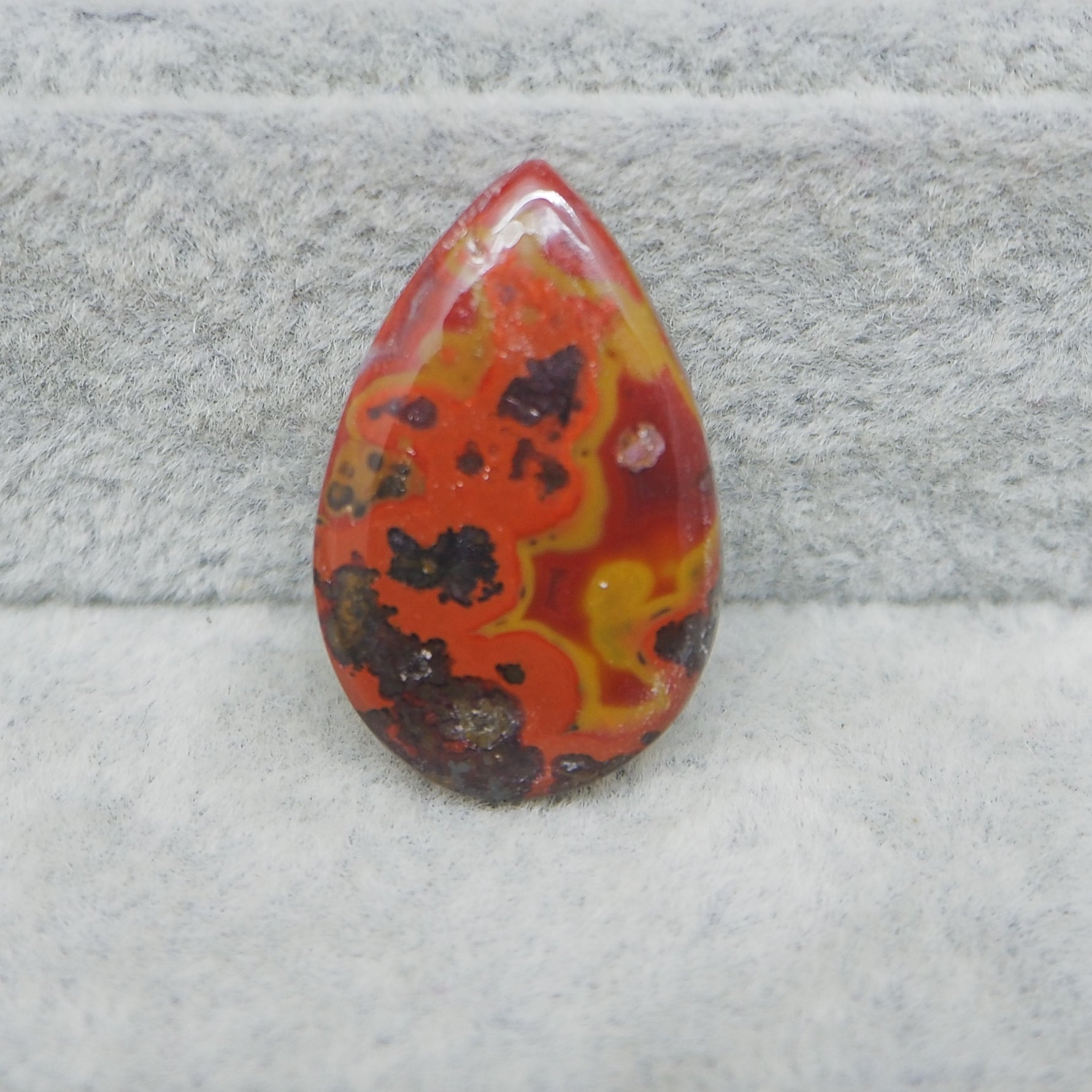 Teardrop-shaped multicolored stone on a textured gray background