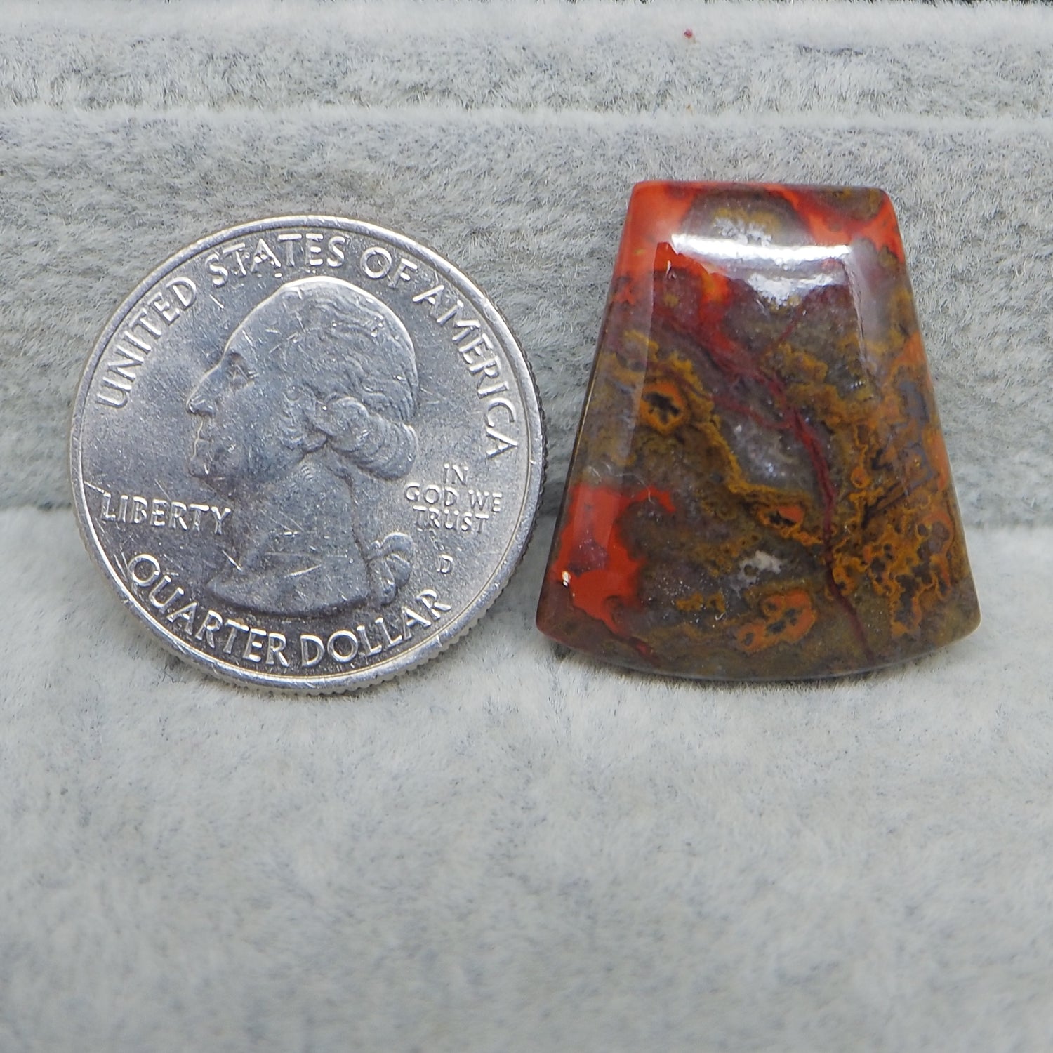 United States quarter dollar coin next to a colorful stone on a gray surface