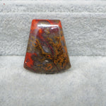 Rectangular stone with red and brown patterns on a textured gray background
