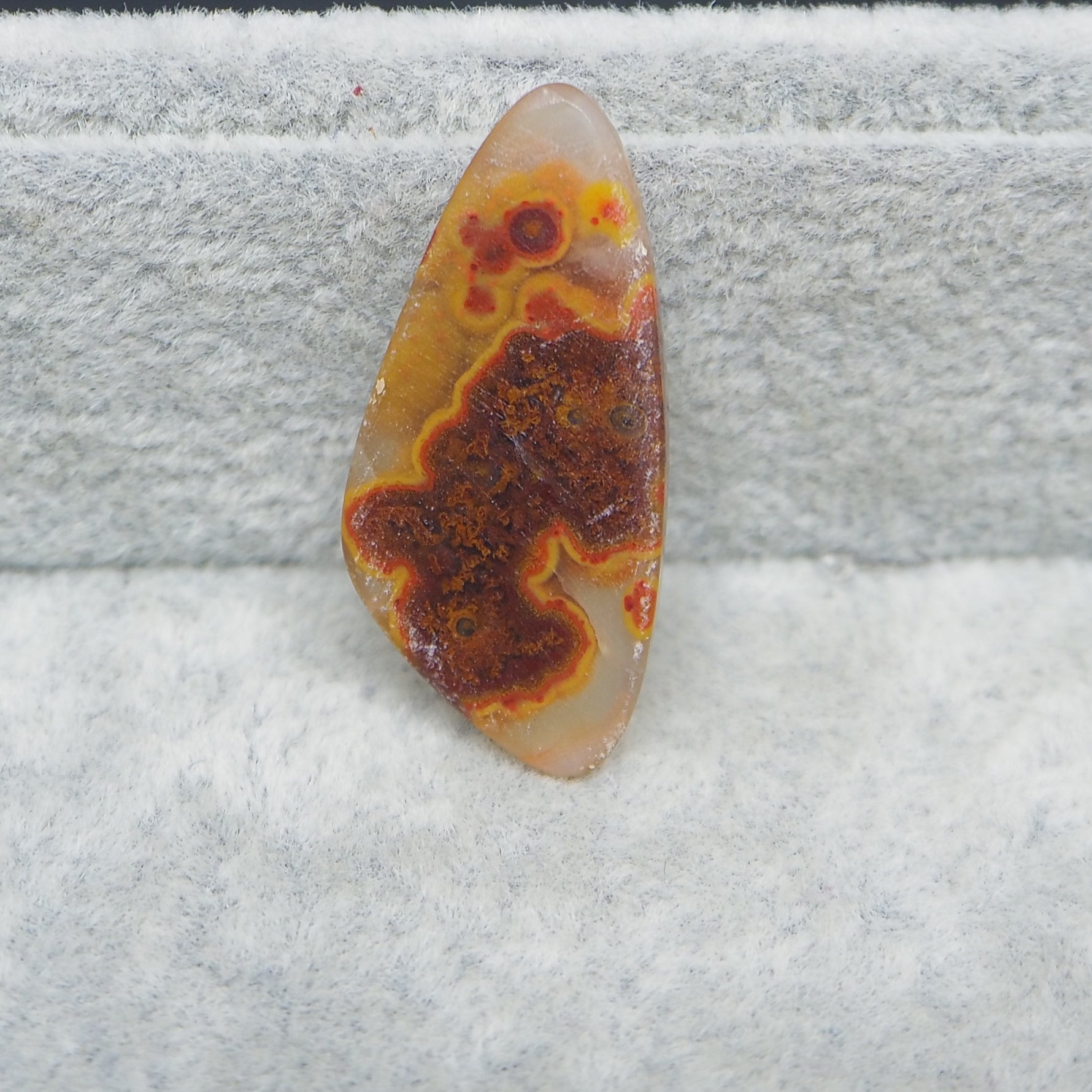 Polished stone with brown and orange patterns on a gray surface