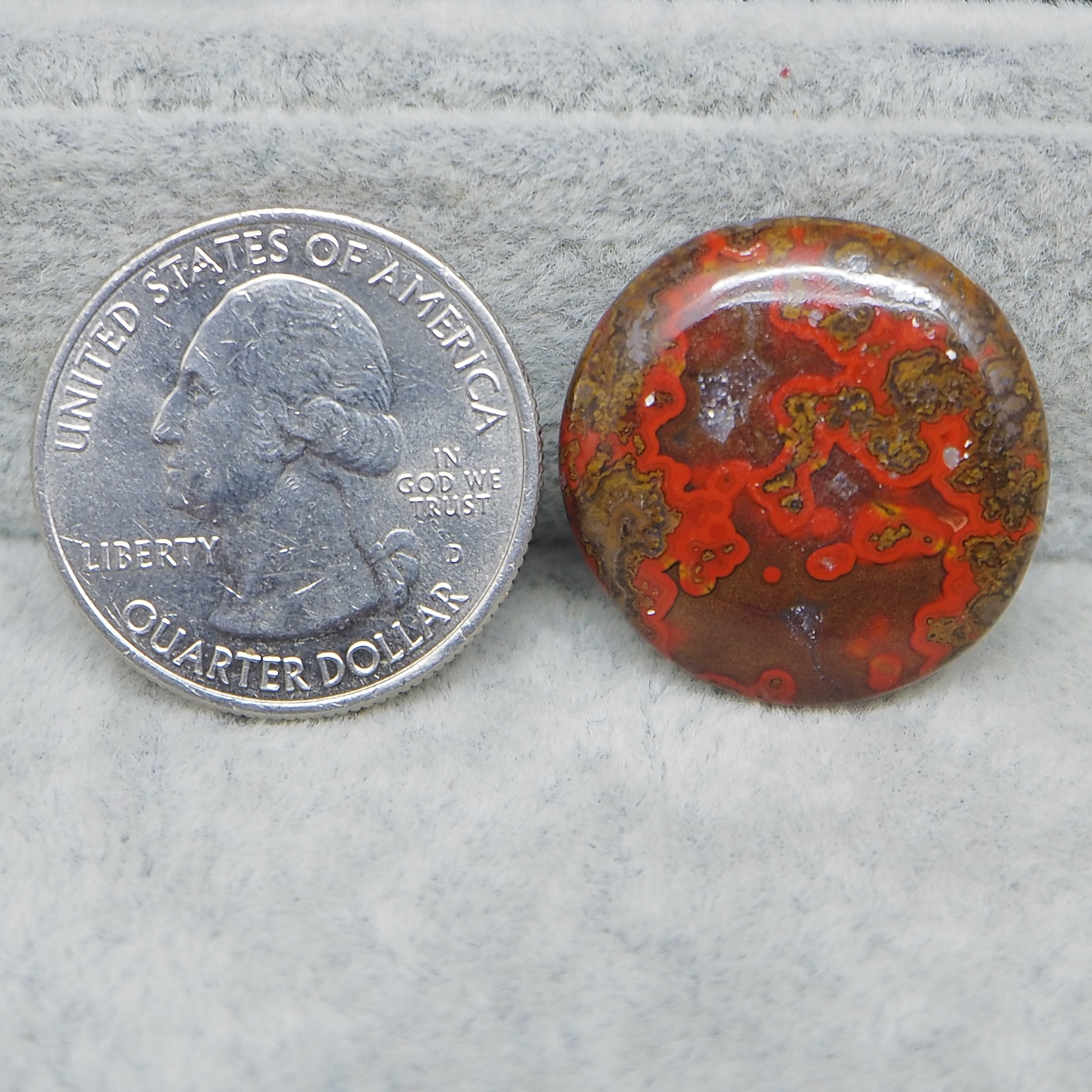 Close-up of a quarter and a red and brown stone on a gray surface