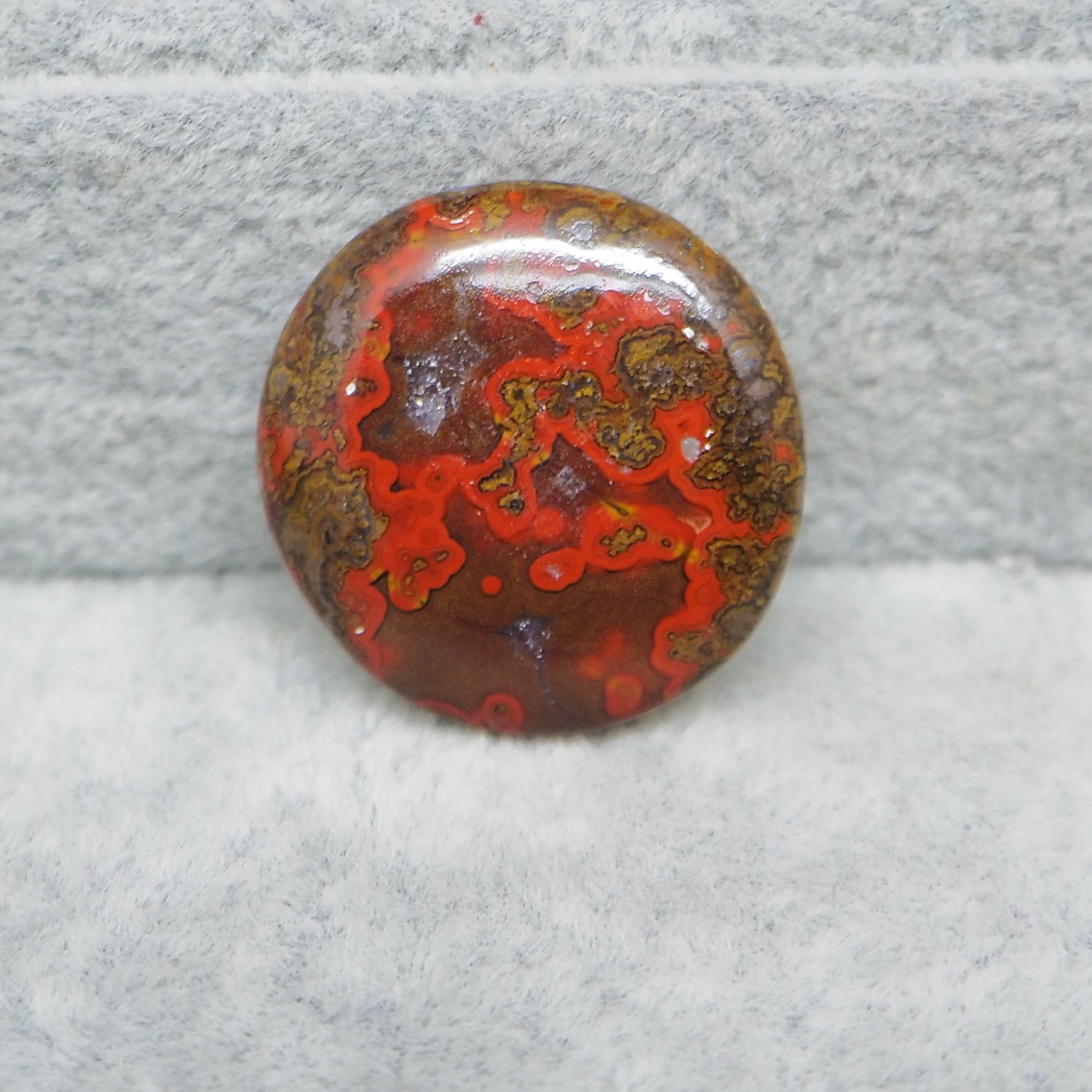 Polished red and brown stone on a gray surface