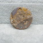 Round, textured stone with a rough surface on a gray brick background