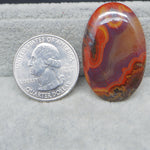 Colorful patterned stone next to a U.S. quarter dollar on a gray background