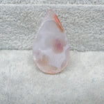 Teardrop-shaped agate stone on a textured gray surface
