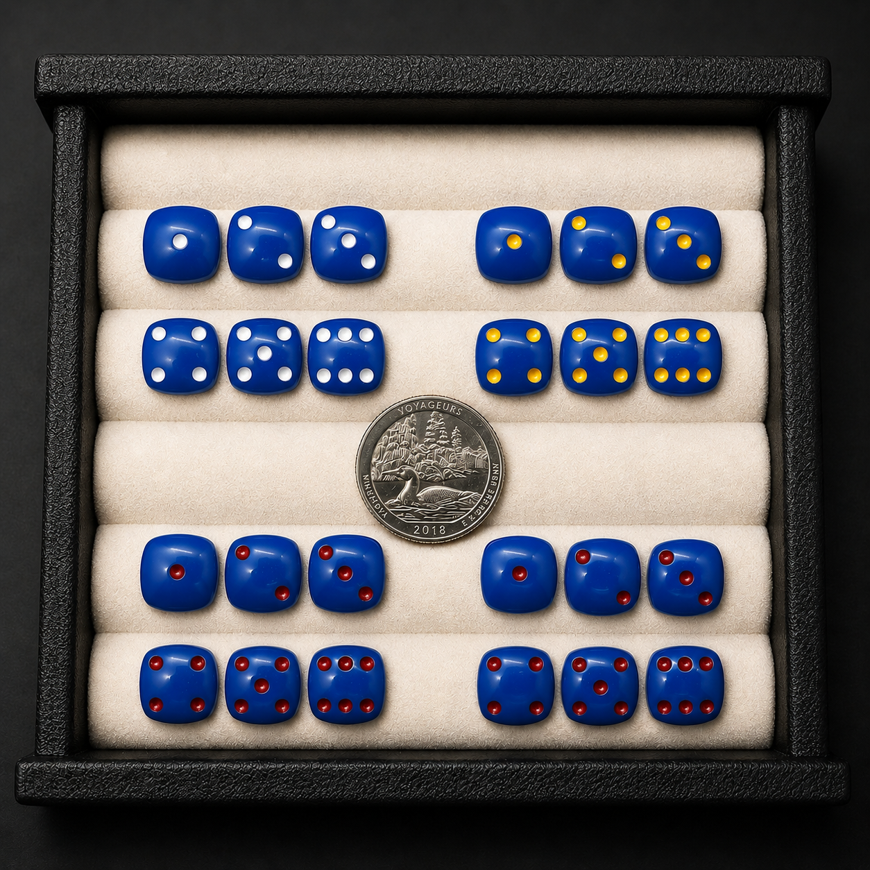 Set of blue dice with different numbers of dots, displayed with a coin for scale.