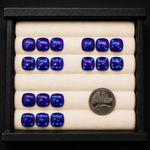 Set of blue stones arranged in a display case with a coin for scale.
