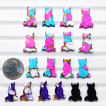 Colorful cat-shaped earrings on a white background with a quarter for scale.