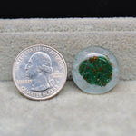 United States quarter dollar coin next to a small round stone with green and red speckles on a textured surface.